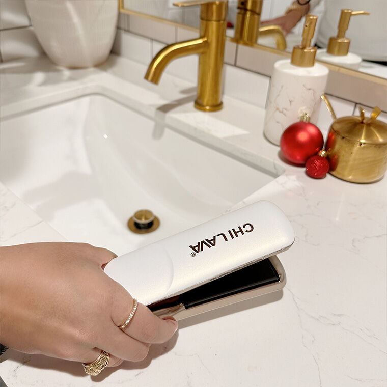 Image of hand holding the Lava Pro MiniStyler near a bathroom sink with a marble countertop