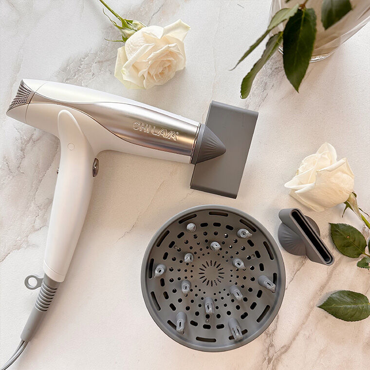 Lava Pro Turbo Hair Dryer laying on a marble counter surrounded by white roses